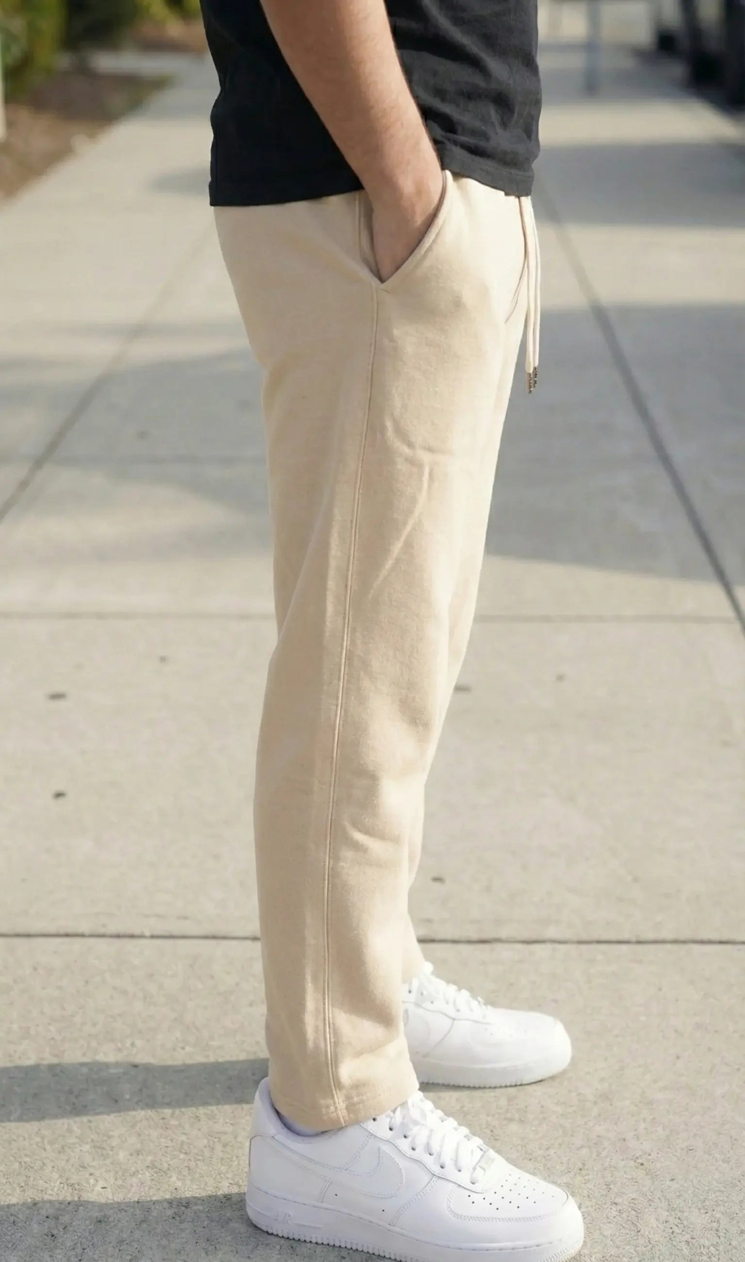 Person wearing beige pants and white sneakers on a sidewalk